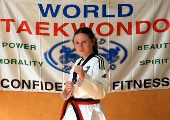 Halle Goeing in her world taekwondo formal uniform, standing proudly in a guarding block position showing confidence and determination.